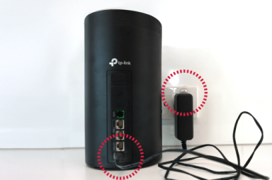 TP-Link modem with highlighted power adapter and ports.
