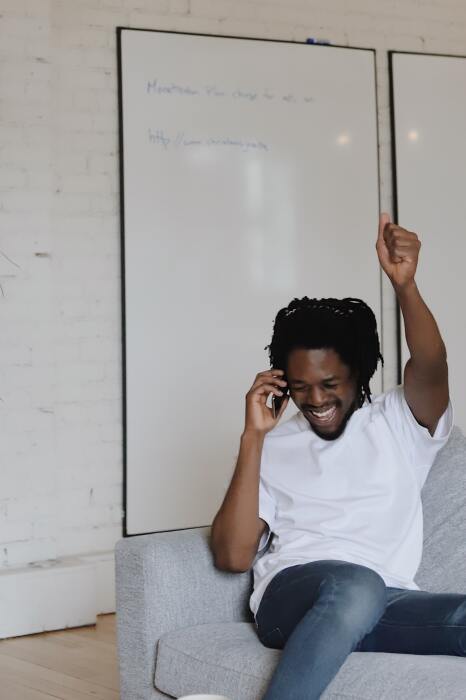A man raising his arm in celebration while on a phone call