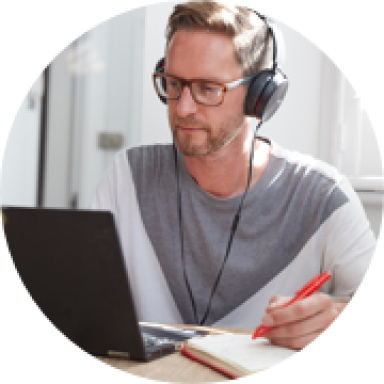 Image of person with headphones on writing in a notepad