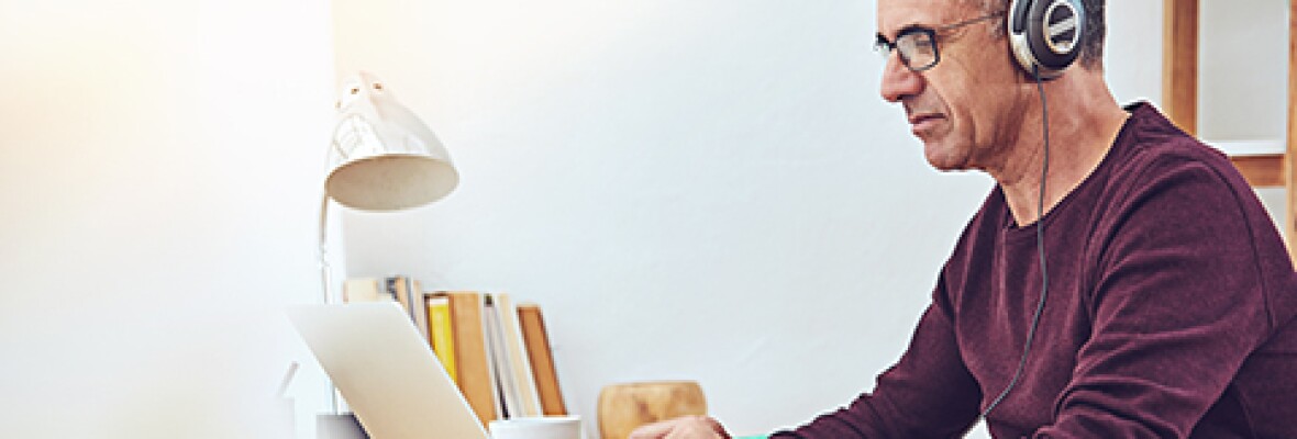 Man working on a laptop wearing a headphone