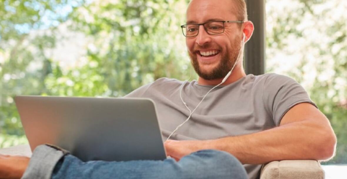 Man working on a laptop wearing earphones