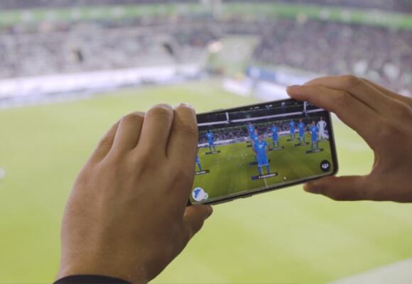 Person holding mobile phone in a stadium