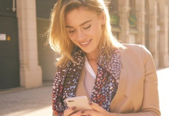 A woman outdoors walking down the street looking at her phone
