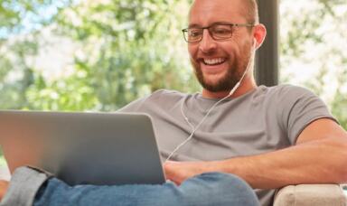 Man working on a laptop wearing earphones