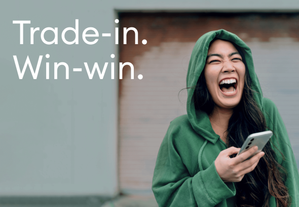 Lady in a hoody, laughing at a message showing on her new phone.