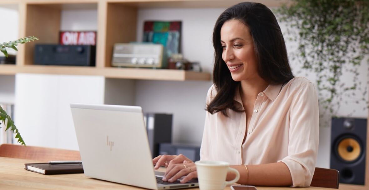 Woman working on laptop with coffee cup on table