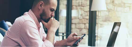 A man looks intently at his mobile phone.