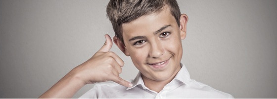 A boy pretends to use his finger and thumb as a phone