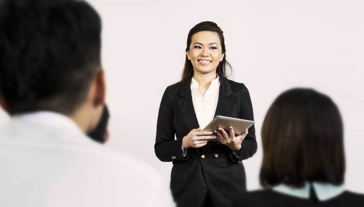 Woman holding a tablet talking to an audience
