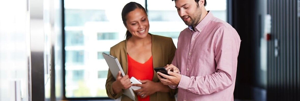 Man showing his mobile phone to a woman in office