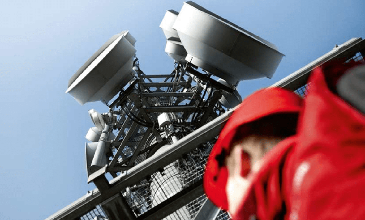 A man looks up at a cell tower