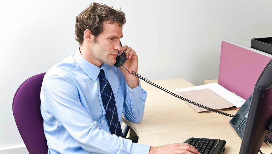 Man talking on phone and working on computer