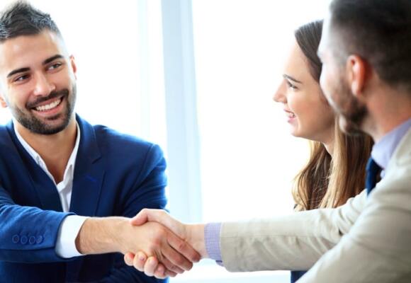 Two men shaking hands and a woman looking at them