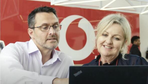 A man and woman talking in front of a laptop at a Vodafone Store