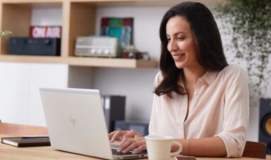 Woman working on laptop with coffee cup on table