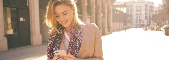 A woman outdoors walking down the street looking at her phone