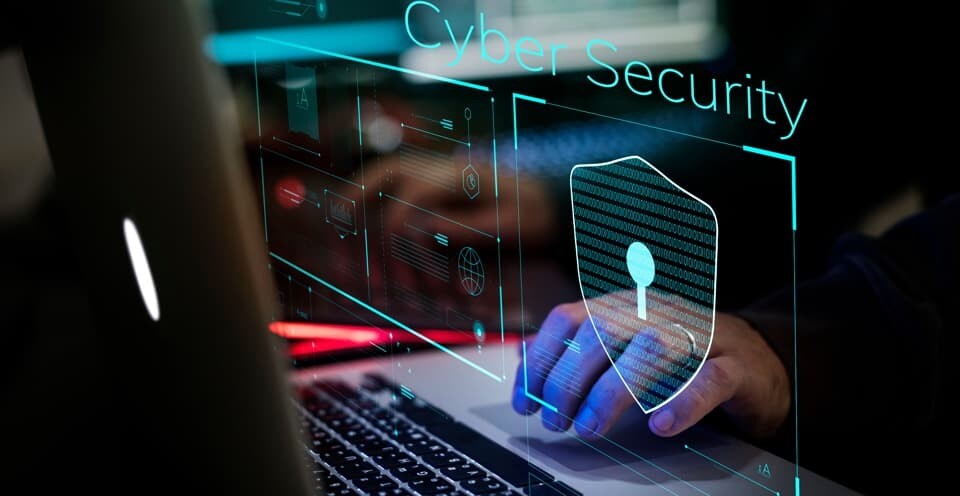 Person working on a laptop showing cyber security logo