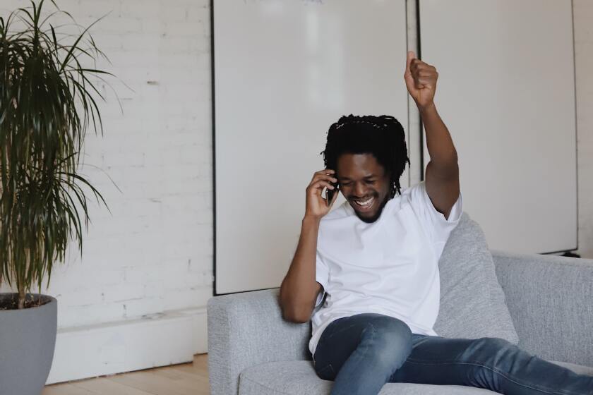 A man raising his arm in celebration while on a phone call