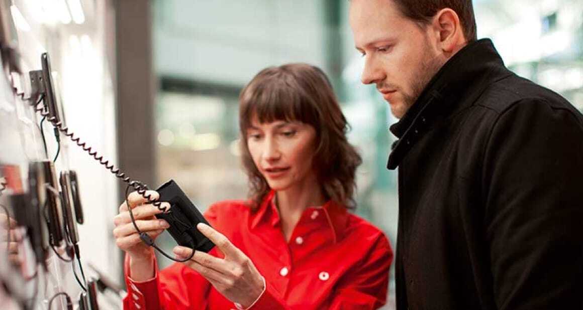 lady in red shirt showing a handset to a man in black coat