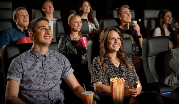 People sitting down inside a cinema and enjoying movies with popcorn