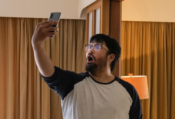 Image of person holding a smart phone above their head looking at it in surprise