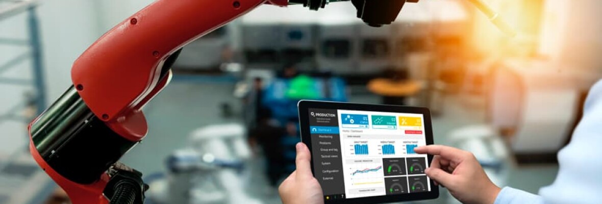 Worker looking at a tablet and machine in a factory