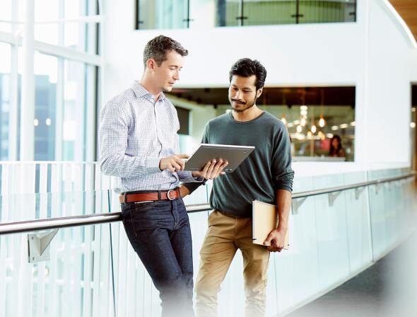 Two men talking over a tablet