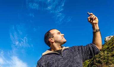 A man holds up his mobile phone to check for signal.