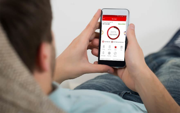 Man laying with a phone looking at My vodafone app