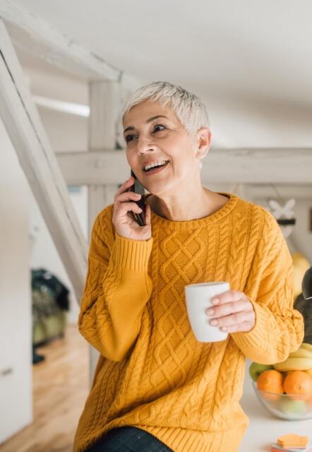 Woman talking on a phone holding a cup