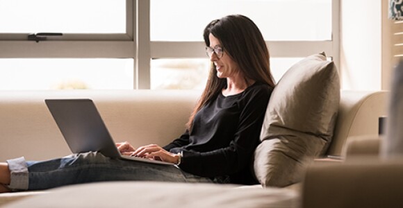 Woman sitting on couch working on a laptop